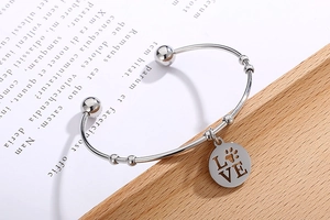 Macro shot of silver open cuff bracelet with LOVE and paw print engraved charm detail