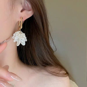 Detail view of a white acrylic pleated flower earring on a model for elegant styling
