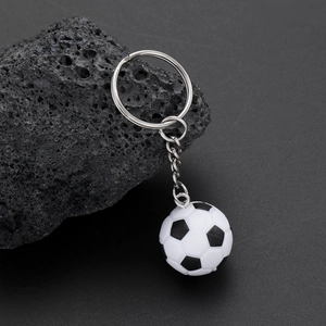 Macro detail of a classic black and white soccer ball keychain on a volcanic rock surface