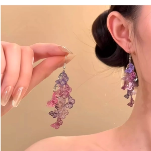 Détail de boucles d'oreilles papillon élégantes avec dégradé violet rose et pompon