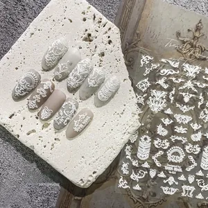 Macro detail of white embossed lace nail stickers with bohemian floral patterns