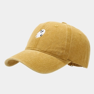Detail of white ghost embroidery on vintage washed yellow cotton baseball cap fabric