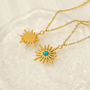 Close-up of golden sunburst pendants with turquoise inlay on a textured tray