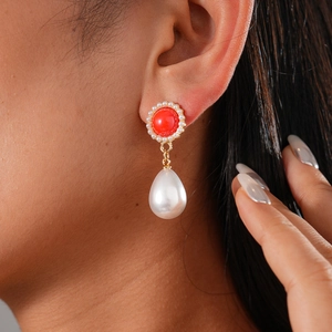 Detail of a red gemstone earring with pearl halo and large white teardrop pearl drop