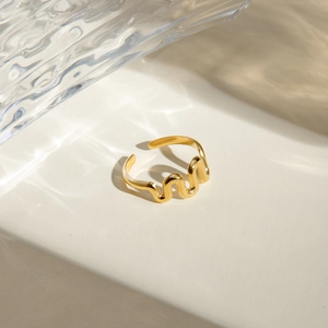 Close-up of golden wave shaped open bangle with rippled light reflections on surface