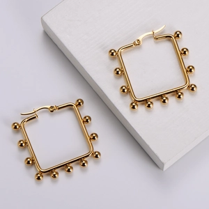 Detail of gold geometric square hoop earrings with small bead edges on white background