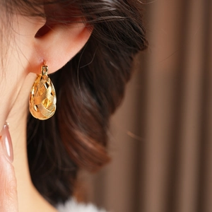 Detailed view of gold woven texture earrings worn by model for elegant luxury style