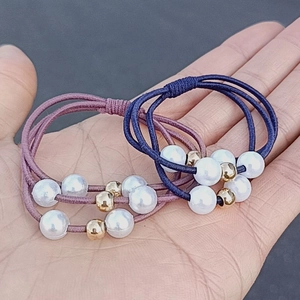 Elastic triple-strand pearl hair ties in navy blue and lilac with gold accent beads