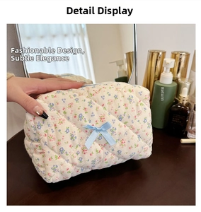 Detail of floral quilted makeup bag with blue ribbon bow on a vanity setup