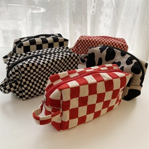 Detail of corduroy makeup bags in checkered and cow prints with zipper and handle