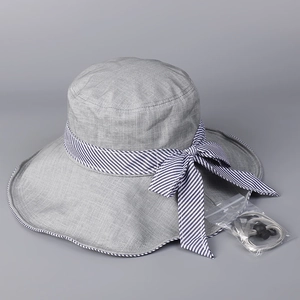 Detail of grey wide brim sun hat with blue-white striped bow and adjustable wind strap
