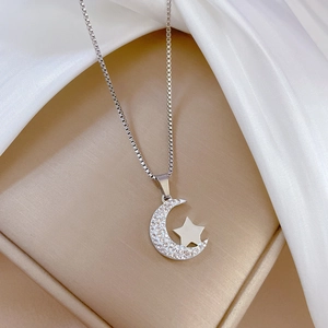 Macro shot of silver crescent moon and star pendant with crystal inlay on a box chain