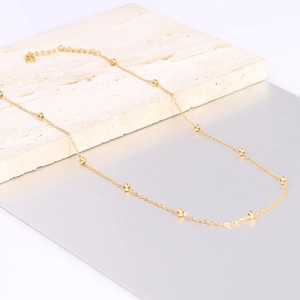Detail of gold bead station necklace with lobster clasp and adjustable chain on stone