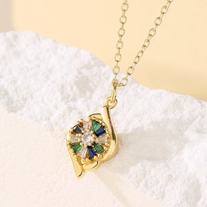 Gold-plated circular pendant necklace with green and blue zircon gemstones on white rock