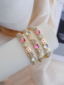 Close-up of three-piece gold-plated bracelet set with pink heart crystals and smiley charms