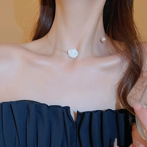 Detail of open gold collar necklace with white camellia flower and pearl pendant