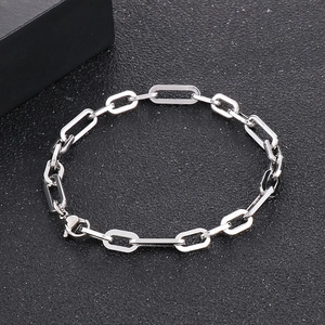 Detailed close-up of polished silver paperclip chain bracelet on textured black background