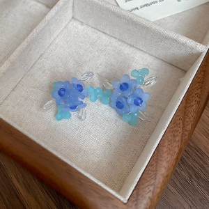 Detail of blue beaded flower earrings with matte acrylic beads in a wooden jewelry box