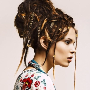 Detail view of golden spiral hair rings and coils styled in brown dreadlocks