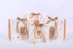 Detail of cartoon bear gift bags in five sizes with golden handles and ribbons