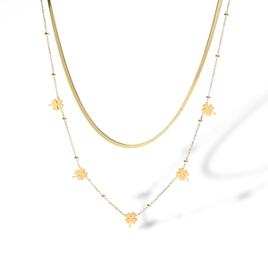 Detail of gold double-layered necklace featuring flat snake chain and clover pendants