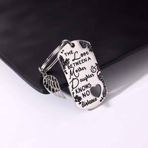 Detail of stainless steel dog tag keychain with feather charm and mother-daughter engraving
