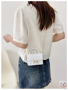 Close-up of a white quilted PVC jelly bag featuring a pearl handle and gold chain strap