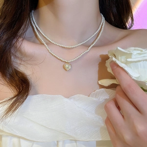 Double-layer pearl necklace featuring a heart pendant and delicate floral tassel style