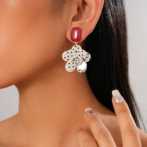 Detail of flower earring with black polka dots and red square stud worn by a model