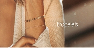 Close-up of elegant gold chain and beaded bracelets on a model's wrist with knitwear