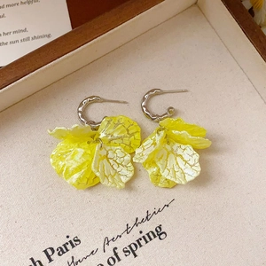 Detailed macro view of yellow resin petal earrings with silver C-shape metal ear hooks