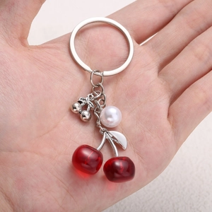 Cute red cherry keychain with white faux pearl pendant held in hand for women bags