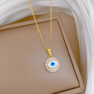 Detailed close-up of golden evil eye pendant with blue center and sparkling white crystals