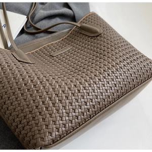 Close-up of deep brown woven leather texture and logo detail on a fashion tote bag