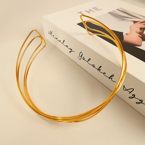 Elegant gold multi-layer spiral choker necklace displayed on a minimalist book background