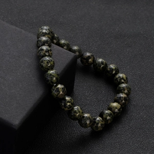 Detailed view of dark green natural stone beaded bracelet on a matte black display box
