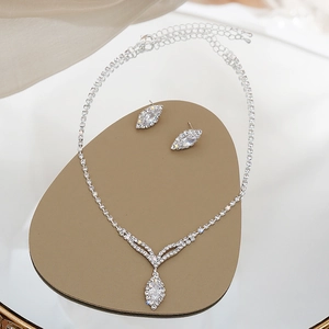 Detailed view of silver zircon tassel necklace and matching earrings set on mirror stand