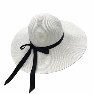 Dettaglio cappello di paglia a tesa larga con elegante fiocco di nastro nero e trama fine