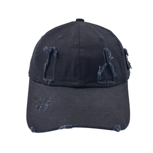 Close-up of distressed vintage black cotton baseball cap showing ripped hole details