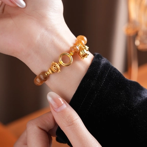 Bracciale di perle in citrina con ciondolo a campana dorato sul polso di una modella
