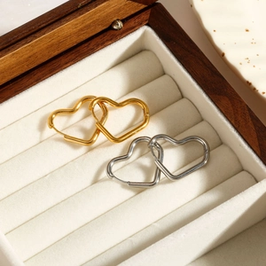 Détail de créoles en forme de cœur en or et argent dans un écrin à bijoux élégant