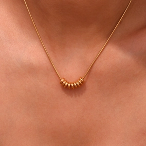 Close-up of a 18K gold plated snake chain necklace with small polished bean pendants