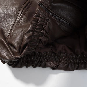 Detail showing deep brown leather texture with high-quality zipper and elastic cuffs