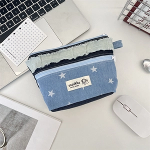 Detailansicht der Denim-Kosmetiktasche mit Sternenmuster und Fransen am Schreibtisch