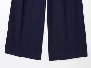 Detail of navy blue pleated trousers showing high-quality twill fabric and hem stitching