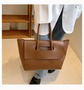 Brown faux leather large tote bag styled with white blazer for modern office commute
