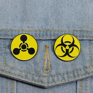 Biohazard and chemical warning enamel pins attached to a blue denim jacket pocket