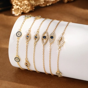 Macro detail of gold evil eye and hamsa hand bracelets with blue zircon stones