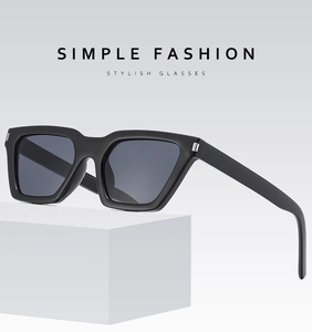 Detail view of square black sunglasses with metal hinges on a minimalist white stand