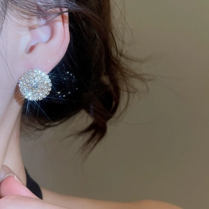 Close-up of a model wearing sparkling round rhinestone stud earrings with a luxury look